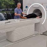  zdjęcie przedstawia technika radiologii wykonującego badanie rezonansu magnetycznego pacjentowi w Pracowni Rezonansu Magnetycznego. 